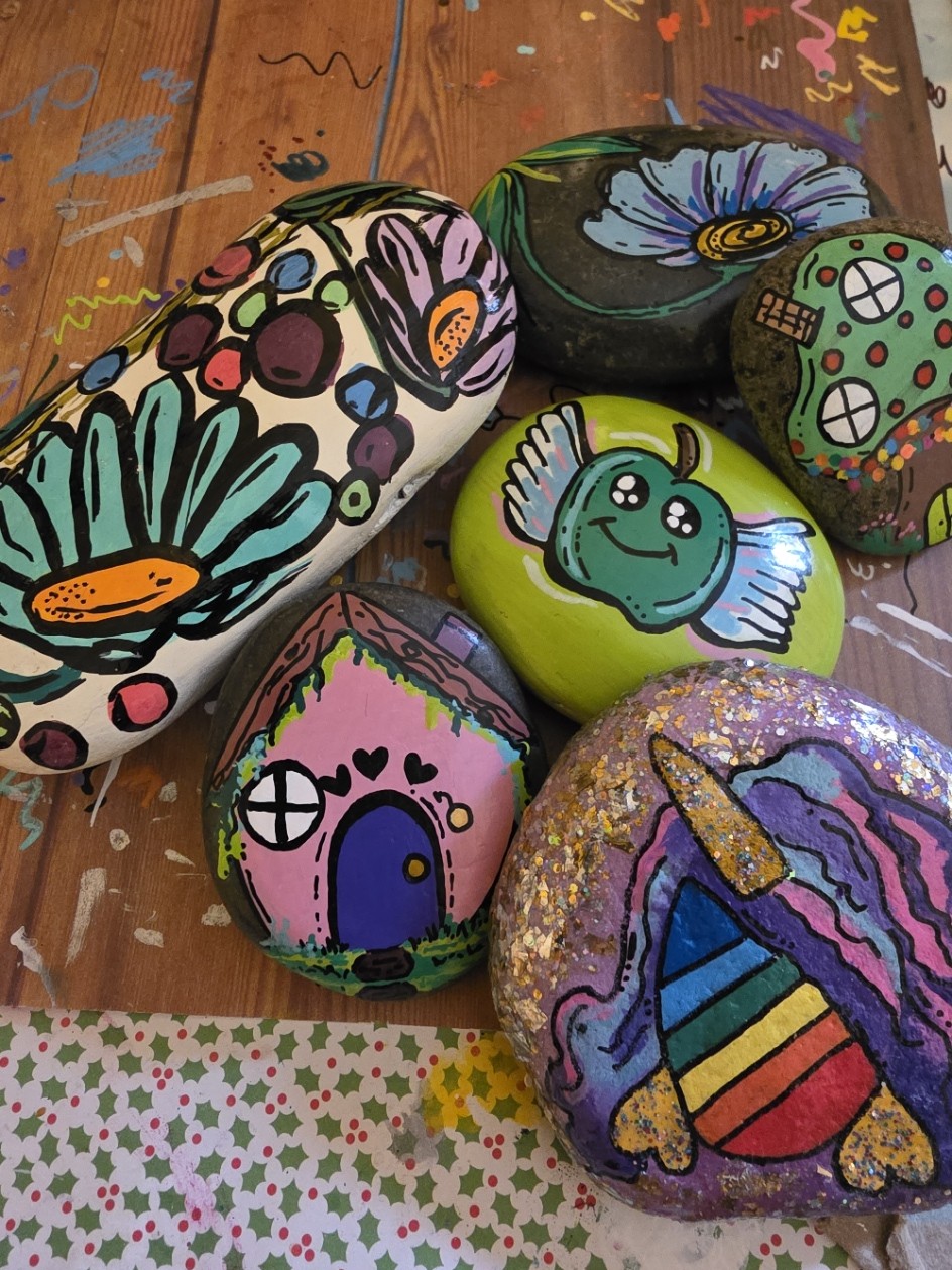 A colorful group of six kindness rocks painted with acrylic paint markers. 